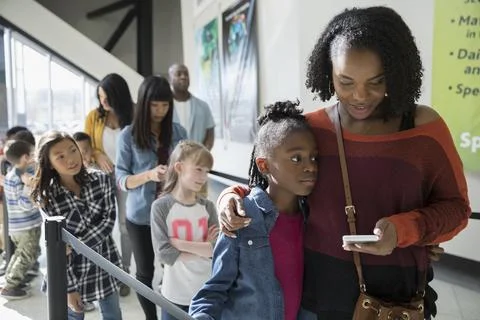Mother and daughter waiting in queue at science center Stock Photos