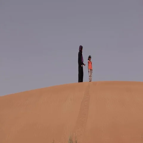 Mother and daughter walking down the desert dunes. Stock Footage 69487341