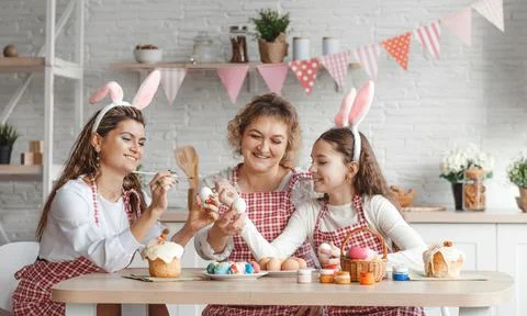 Mother and daughters draw Easter eggs. A happy family is preparing for Easter Stock Photos