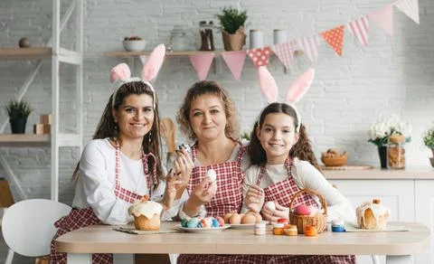 Mother and daughters draw Easter eggs. A happy family is preparing for Easter Stock Photos