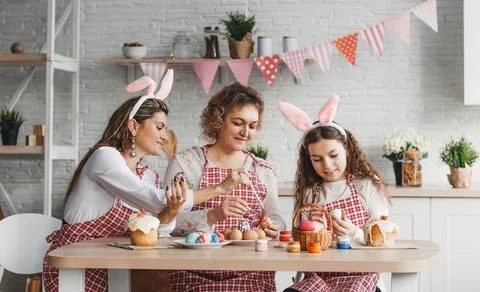 Mother and daughters draw Easter eggs. A happy family is preparing for Easter Stock Photos