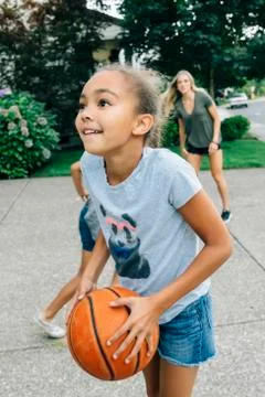 Mother and daughters playing basketball in driveway Stock Photos