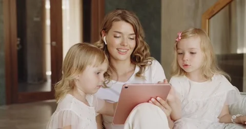 Mother and daughters sitting at the sofa and watching funny cartoon together Stock Footage 217423764