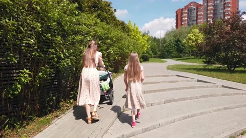 Mother and daughters walking in the summer city park Stock Footage 132620587