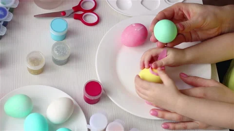 Mother and daugter hands decorating egg. happy easter scene top view close up 스톡 동영상 147862012