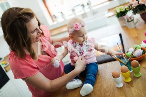 Mother and her baby painting easter eggs Stock Photos