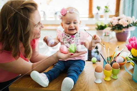 Mother and her baby painting easter eggs Stock Photos
