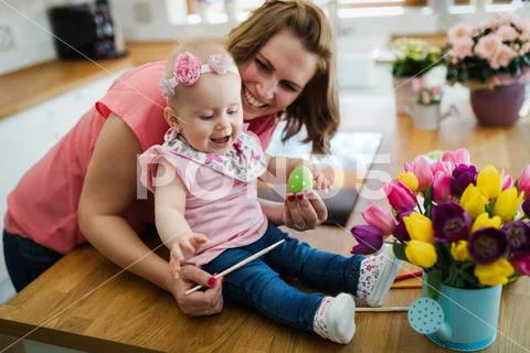 Mother and her baby painting easter eggs Stock Photos