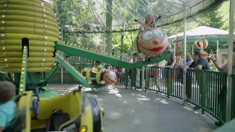 Mother and her little baby boy are riding on caterpillar in the amusement park Stock Footage