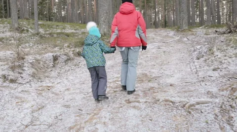 Mother and her little daughter walking through a snowy forrest. Steadicam. Video stock 59759082