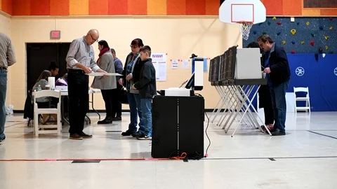 A mother and her son insert her ballot in a scanner. Stock-Footage 126219000