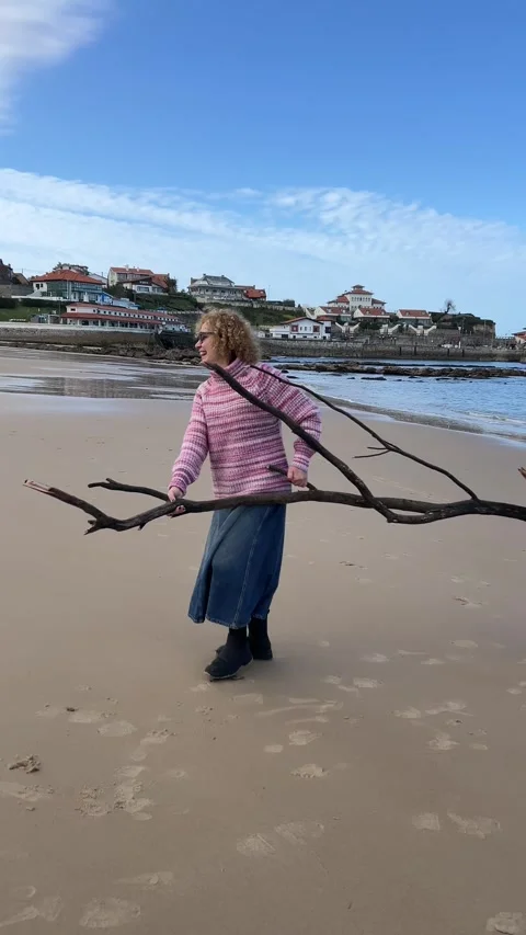 A mother and her son remove a tree trunk from the beach. Stock Footage 266161306