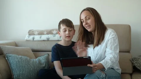 Mother and her son using video chat on tablet at home and sitting on sofa 스톡 동영상 126962672
