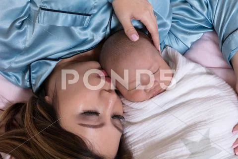 Mother and infant baby boy sleeping close together while in bed Stock Photos