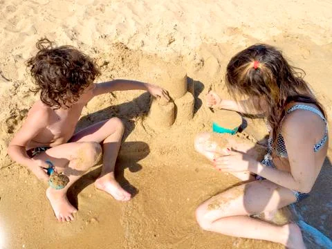 Mother and kid making castles of sand at tropical beach and having fun. Stock Photos