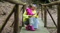 Mother and little daughter with smartphone on foot bridge in forest HD Footage
