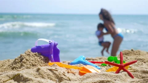 Mother and little son playing at the sea beach, sand toys in front Stock Footage