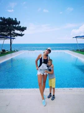 Mother and son on the background of a rectangular pool near the sea Stock Photos