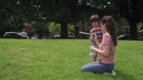 A mother and son blow bubbles in a park field on a summer day Video stock 143622553