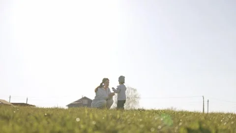 Mother and son blowing soap bubbles in a grassy meadow Stock Footage 335522803