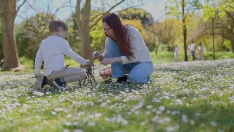 Mother and son building a twig structure in a field of daisies Stock Footage 309868534
