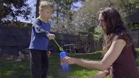 Mother and son create bubbles in a sunny backyard Stock Footage 74118048