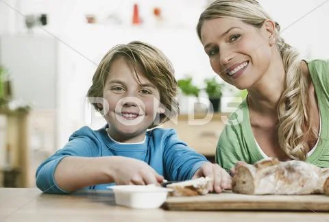 Mother and son cutting bread in kitchen Stock Photos