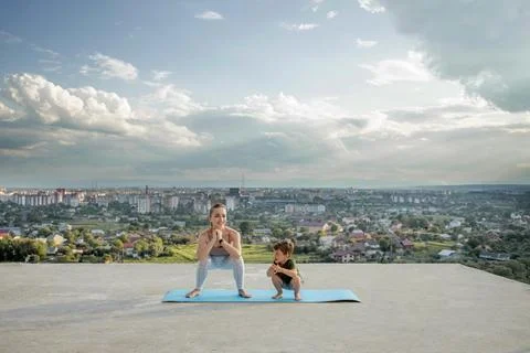 Mother and son doing exercise on the balcony in the background of a city duri Stock Photos