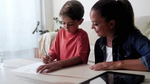 Mother and son doing homework for elementary school at home. Parent help child  Stock Footage 277336942