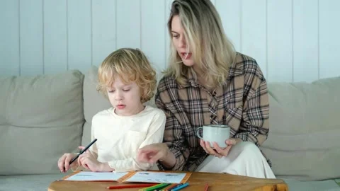 Mother and son doing homework while sitting on the couch at home Video stock 296447599