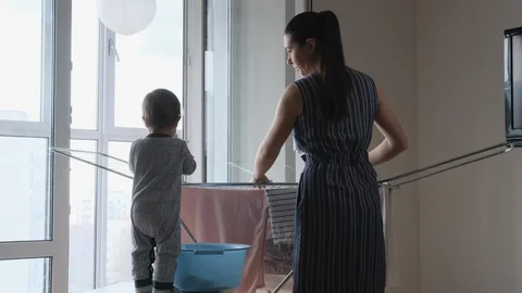 Mother and son during sharing house chores, they hang laundry after washing.  Stock Footage 128981378