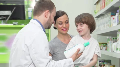 Mother and son engaging with a friendly pharmacist at the drugstore Stock Footage 311985147