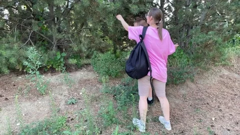 Mother and son explore a pine forest, throwing cones into the trees. 動画素材 316208998