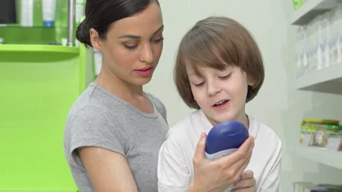 Mother and son exploring shower gel options at a vibrant drugstore Stock Footage 311935708