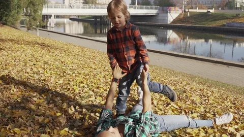 Mother and son having fun in the autumn Park and lying in a pile of yellow Video stock 97104334