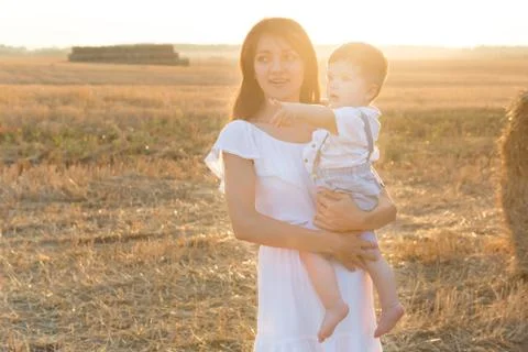 Mother and son. Hay stack or bale on yellow field. Stock-Fotos