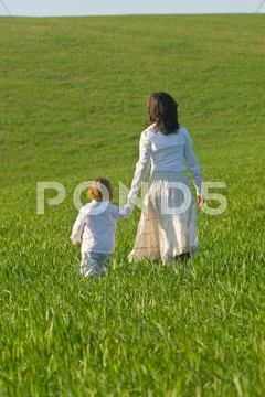 Mother And Son Holding Hands In Field Rear View