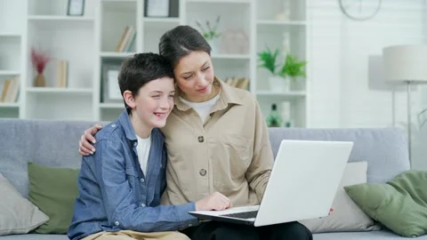 Mother and son hugging together sitting on sofa at home in living room watching  Stock Footage 238629524