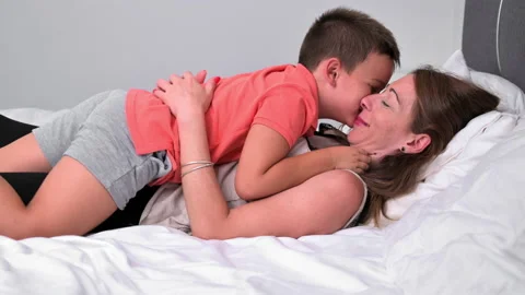 Mother and son hugging while lying on bed and enjoying happy moments together Stock Footage 214479018
