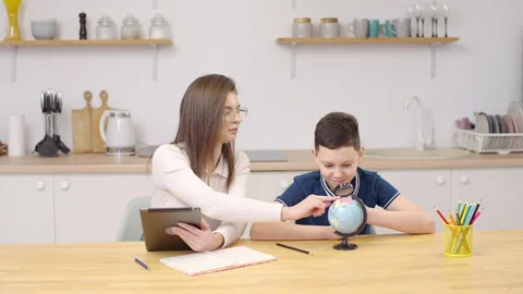 Mother and son in kitchen with tablet for studying, learning at home together 스톡 동영상 263021325