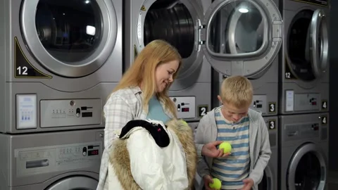 A mother and son in the laundry room are going to wash a down jacket. Stock Footage 346443090
