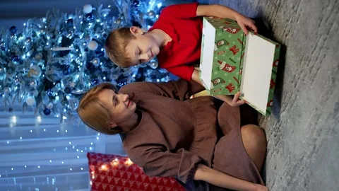 Mother and son open boxes from Santa under the Christmas tree. Stock Footage 258357724