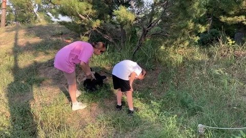 Mother and son pack their backpack and leave their picnic spot in the sunny Stock Footage 317082136