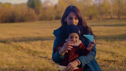 A mother and son playing with paper airplanes in an autumn park. Family bonding, Stock Footage 266417006