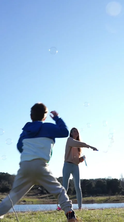 Mother and son playing with soap bubbles in nature Stock Footage 276528164