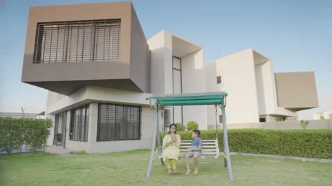 Mother and son playing together outside modern luxury house Stock Footage