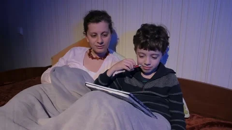 Mother and son read bedtime stories. Covered with a plaid. Tells stories. Stock Footage 131042377