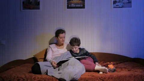 Mother and son read bedtime stories. Covered with a plaid. Flying shadows. Stock Footage 131042572