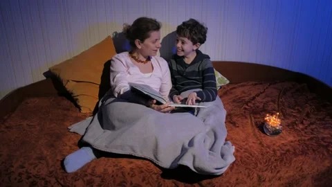 Mother and son read bedtime stories. Covered with a plaid. Tells stories. Stock Footage 131043199
