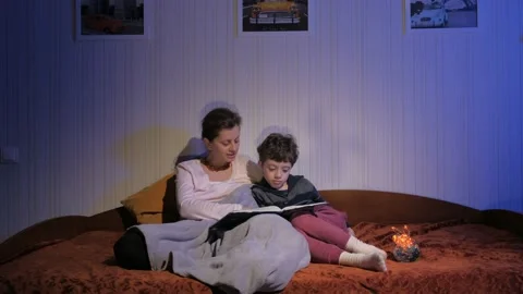 Mother and son read bedtime stories. Covered with a plaid. Flying shadows Stock Footage 131043205
